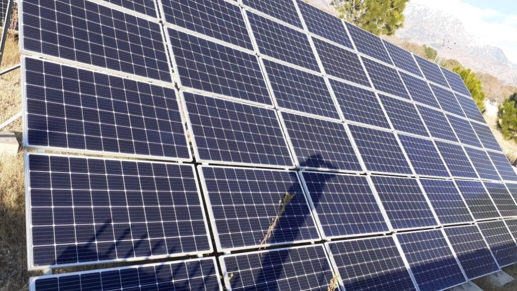 Solar panels on a steel frame on a hillside in Swat, KPK, with bare mountains behind